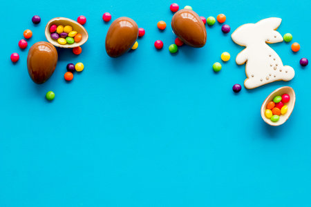 Easter sweets frame. Chocolate eggs and bunny gingerbread on blue background top-down frame copy...