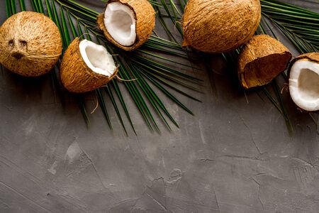 Coconuts and leaves - tropical still life on grey background top-down.