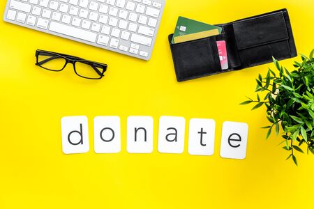 Donate text. Donation online concept with bank card and keyboard on yellow background top-down.の写真素材