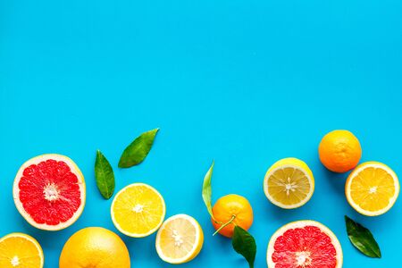 Citrus fruits frame - halfs of lemons, grapefruits, leaves - on blue background top-down.の写真素材