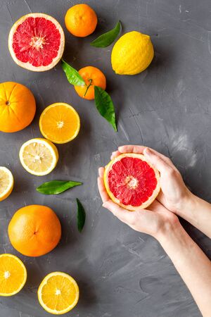 Fresh citrus background with fruit in hands. Oranges, grapefruits, leaves on grey background top-down.の写真素材