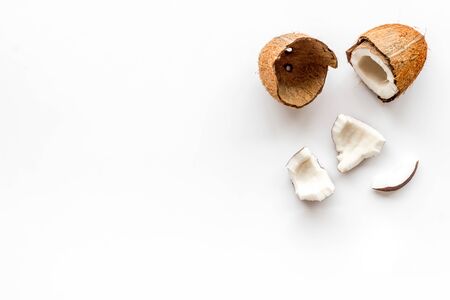 Coconuts frame - halfs and scattered pieces - on white background top-down.