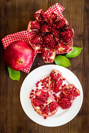 Juicy pomegranate with seeds on plate on dark wooden table top-down.の写真素材