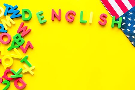 English text near American flag and letters on yellow background top-down.の写真素材