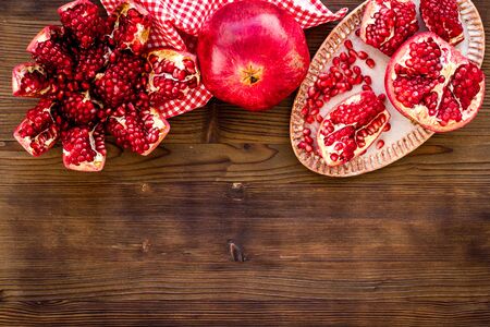 Juicy pomegranate with seeds on plate on dark wooden table top-down.の写真素材