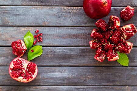 Ripe pomegranate fruit near leaf on dark wooden background top-down.の写真素材