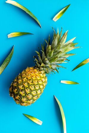 Pineapple on blue background with leaves top-down.の写真素材