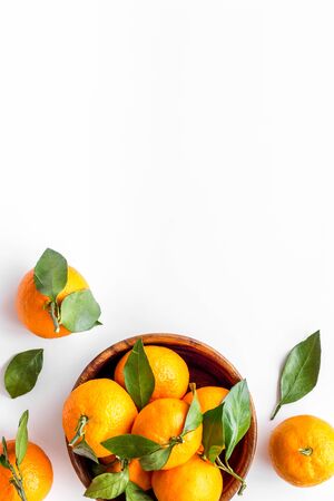 Ripe tangerines on white table. Citruses with green leaves in bowl top-down.の写真素材