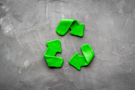 Recycling symbol - green arrows - on grey background top-down.