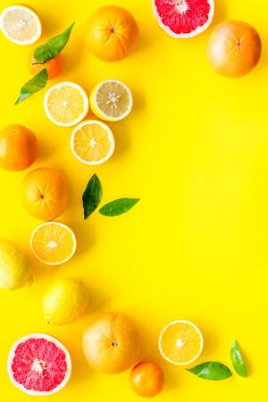 Fresh citrus frame. Oranges, tangerines, grapefruits, leaves on yellow background top-down.の写真素材