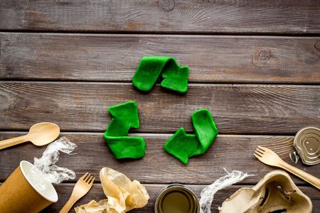 Recycle concept. Green arrows icon among waste on dark wooden background top-down.の写真素材