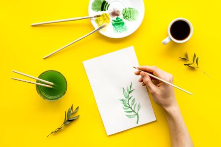 Painting. Female hands draw herbs on yellow background top-down.の写真素材