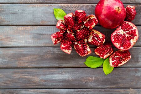 Ripe pomegranate fruit near leaf on dark wooden background top-down.の写真素材