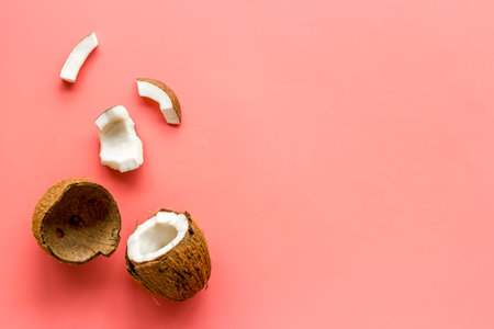 Coconuts frame - halfs and scattered pieces - on pink background top-down.