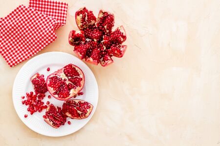 Juicy pomegranate with seeds on plate on beige table top-down copy spaceの写真素材