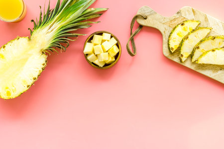 Pineapple juice on pink table with half of fruit top-down.