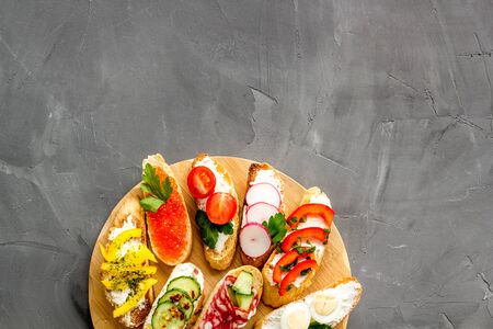 Set of bruschetta on cutting board on grey background top-down copy space