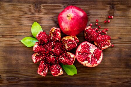 Cut pomegranate with ripe seeds on dark wooden background top-down.の写真素材