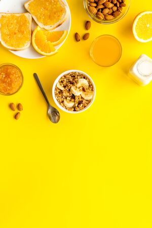 Morning granola near toast and oranges on yellow background top-down.の写真素材