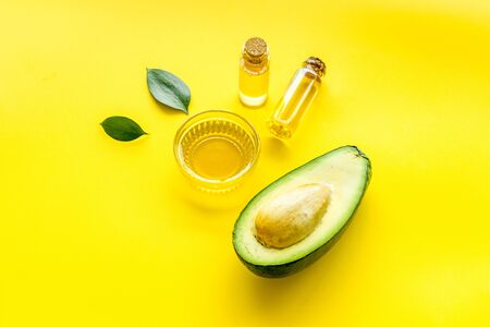 Avocado oil for cosmetology. Sltill lfe with half of fruit and bottles on yellow background.の写真素材