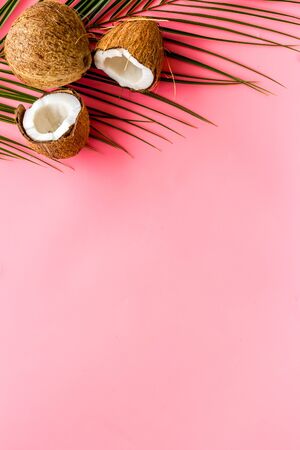Exotic background with coconuts and palm leaves on pink background top-down frame copy spaceの写真素材