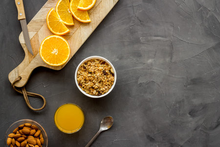 Morning granola near toast and oranges on grey background top-down frame copy space