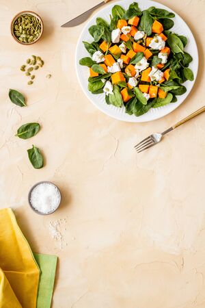 Vegeterian meal concept. Salad with pumpkin and basil on beige background top-down.の写真素材