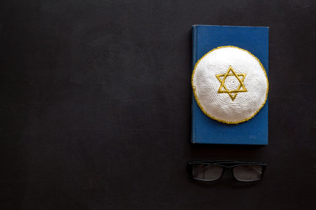 Jewish Kippah Yarmulkes hats with Star of David on Prayer book. Religion Judaisim symbols on black...