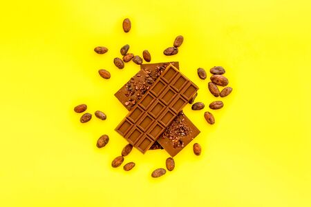 Chocolate - stack of dark bars - on yellow background top-down.の写真素材