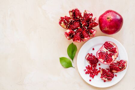Juicy pomegranate with seeds on plate on beige table top-down.の写真素材