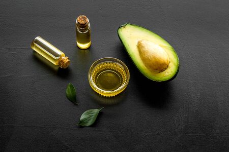 Avocado oil for cosmetology. Sltill lfe with half of fruit and bottles on black backgroundの写真素材