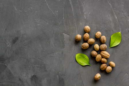 Nutmeg - whole nuts near leves - on grey background top-down copy space