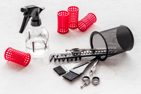 Hairdresser desk with combs, scicoors, spray and curlers on white background.