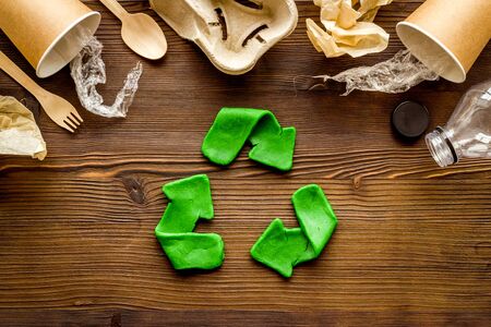 Recycle concept. Green arrows icon among waste on dark wooden background top-down.の写真素材