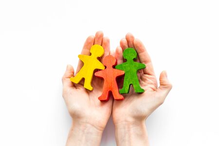 Social protection, insurance, security and safety concept. Hands take care of wooden human figures - white deck, top viewの写真素材