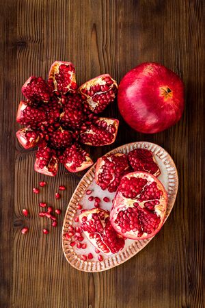 Cut pomegranate with ripe seeds on dark wooden background top-down.の写真素材