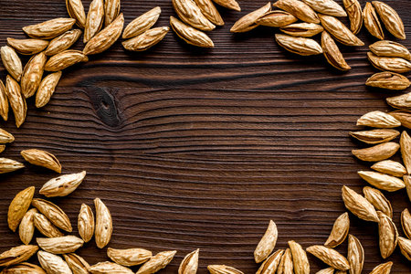 Unpeeled raw almond on dark wooden table top-down frame copy space