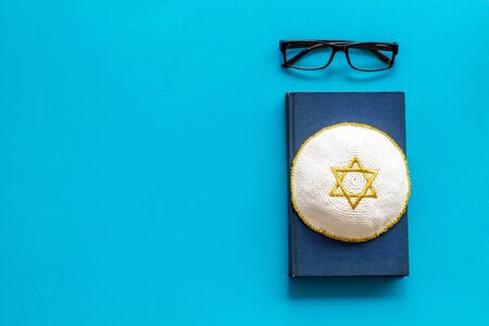 Jewish Kippah Yarmulkes hats with Star of David on Prayer book. Religion Judaisim symbols on blue table. Top view, space for textの写真素材