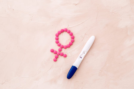 Pregnancy test with two strips and Venus sign - baby girl expectation - on beige background top-down