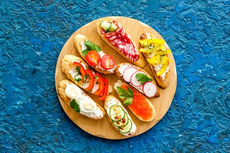 Set of bruschetta on cutting board on blue background top-downの写真素材