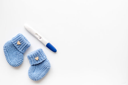 Positive pregnancy test. Baby boy concept with blue accessories on white background top-down copy...
