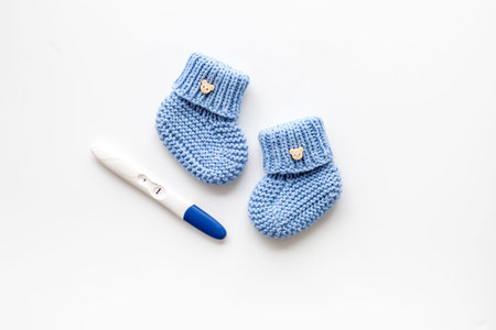 Positive pregnancy test. Baby boy concept with blue accessories on white background top-down