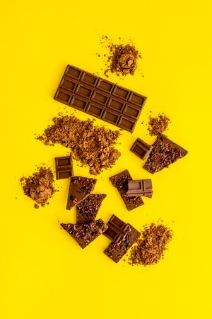 Chocolate frame. Broken bars and cocoa powder on yellow background.の写真素材