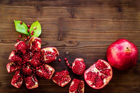 Ripe pomegranate fruit near leaf on dark wooden background top-down.の写真素材