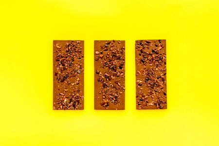 Dark chocolate bars pattern on yellow background top-down.