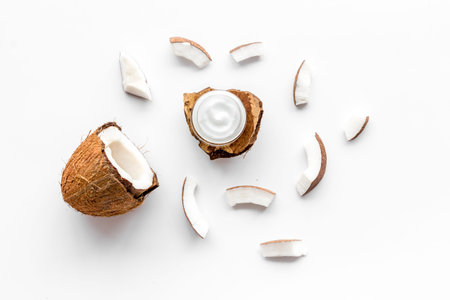 Skin care cream with coconut oil on white background top-down