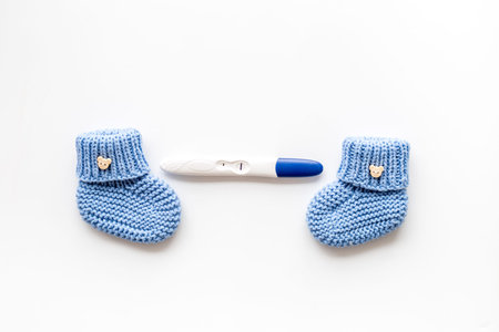 Positive pregnancy test. Baby boy concept with blue accessories on white background top-down