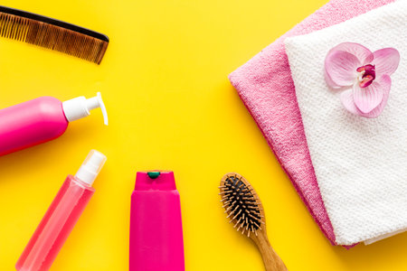 Hair care set with shampoo and towel - pink - on yellow background top-down.の写真素材