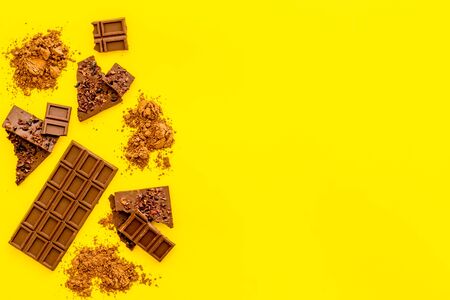 Chocolate frame. Broken bars and cocoa powder on yellow background.の写真素材