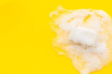 Soap bar with foam on yellow background top-down.の写真素材